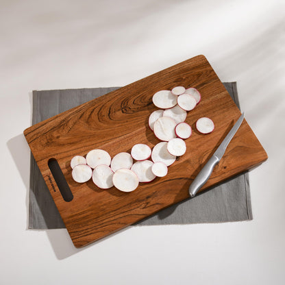 WOOD CURLS Terra rectangular wooden chopping board with natural grain, handle, and sliced radishes on a grey mat.